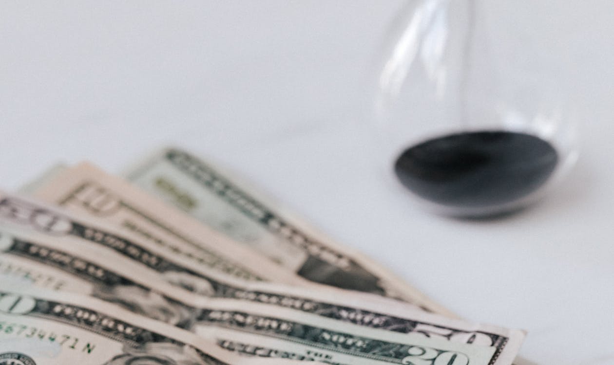 Hourglass beside a stack of US dollar bills, illustrating the relationship between time and money in software development